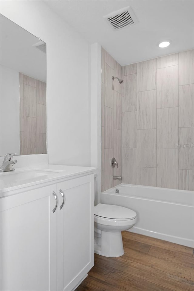 full bathroom with vanity, toilet, wood-type flooring, and tiled shower / bath