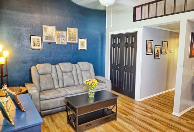 living room featuring wood finished floors, baseboards, and a high ceiling