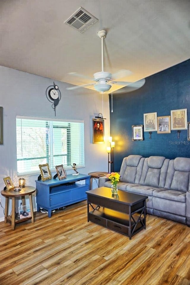 living room with a ceiling fan, wood finished floors, and visible vents
