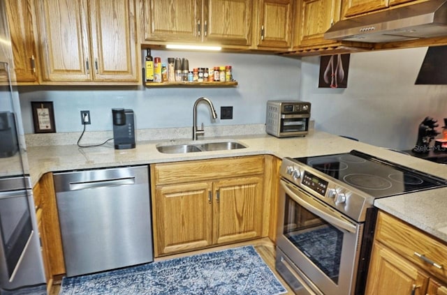 kitchen featuring a sink, appliances with stainless steel finishes, under cabinet range hood, and light stone countertops