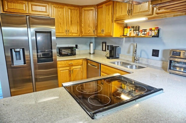 kitchen with brown cabinets, appliances with stainless steel finishes, a sink, and light stone counters