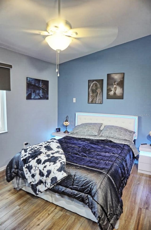 bedroom featuring baseboards, wood finished floors, and ceiling fan