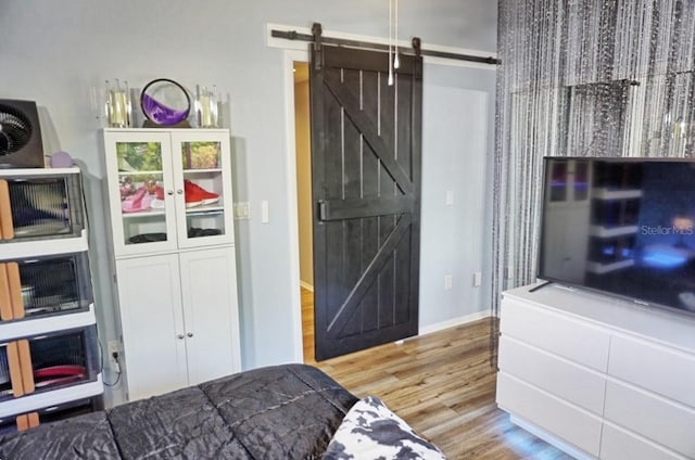 bedroom with baseboards, a barn door, and wood finished floors
