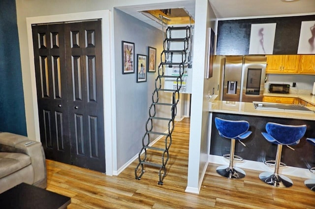 kitchen featuring light wood-type flooring, light countertops, stainless steel fridge, and baseboards