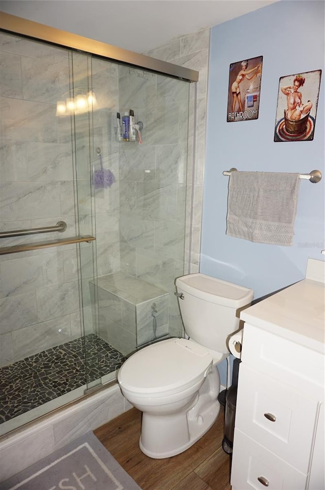 bathroom featuring toilet, a stall shower, wood finished floors, and vanity