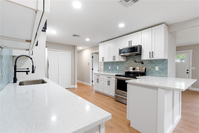 kitchen featuring appliances with stainless steel finishes, light hardwood / wood-style flooring, white cabinetry, and sink