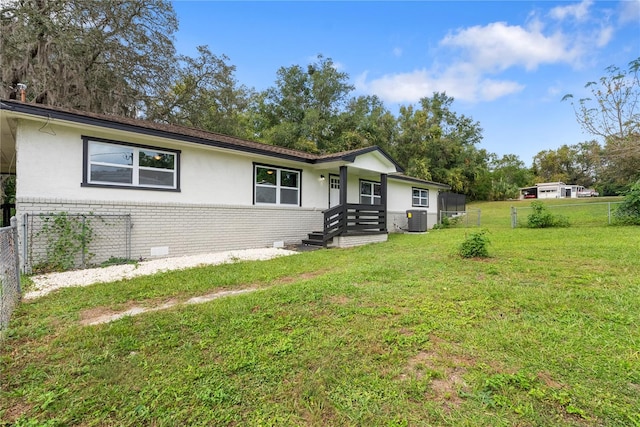 view of front of home with central AC and a front lawn