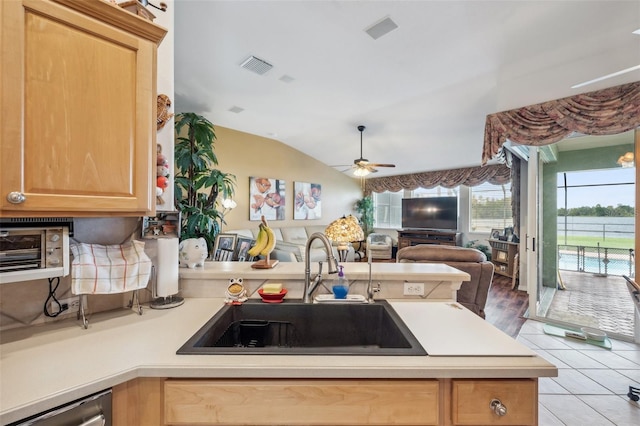 kitchen featuring kitchen peninsula, ceiling fan, light tile patterned floors, vaulted ceiling, and sink