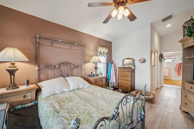 bedroom featuring ceiling fan, lofted ceiling, light wood-type flooring, and ensuite bathroom