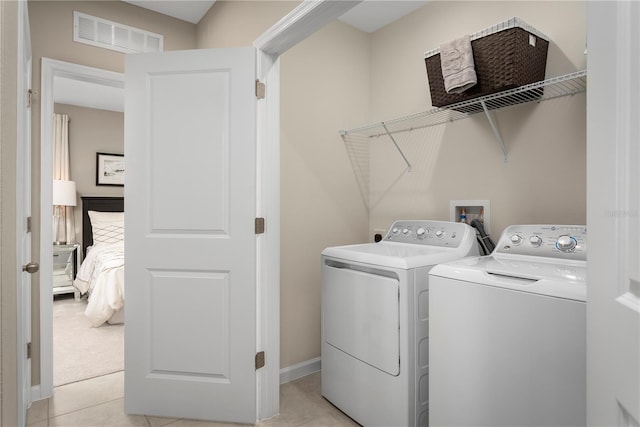 washroom with washer and clothes dryer and light tile patterned floors