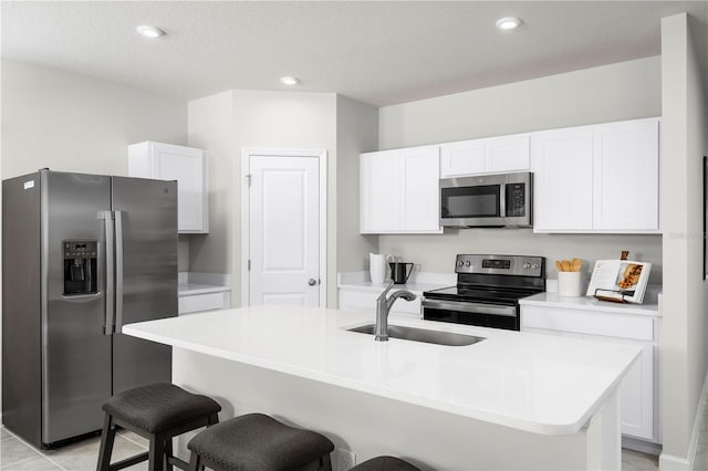 kitchen featuring appliances with stainless steel finishes, sink, an island with sink, a kitchen bar, and white cabinetry