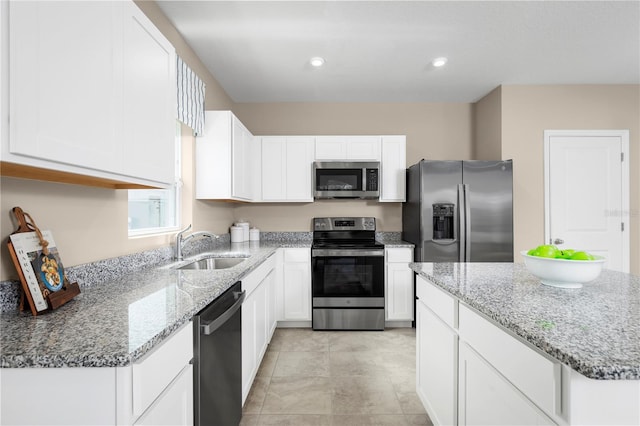 kitchen with sink, appliances with stainless steel finishes, light stone counters, and white cabinetry