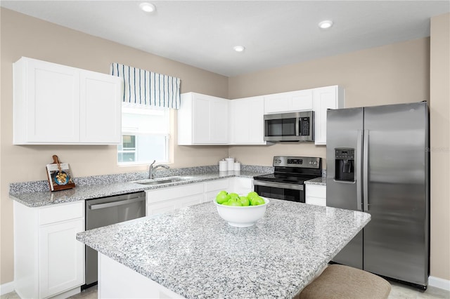 kitchen featuring stainless steel appliances, sink, a kitchen island, and white cabinets