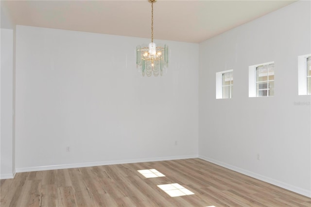 spare room featuring an inviting chandelier and light wood-type flooring