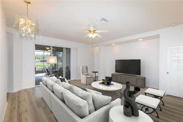 living room featuring ceiling fan with notable chandelier and light wood-type flooring