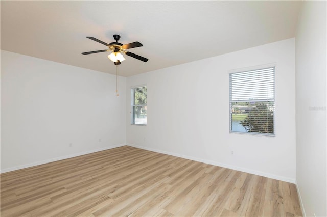 spare room with light wood-type flooring, a healthy amount of sunlight, and ceiling fan