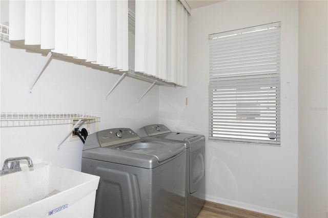 clothes washing area featuring sink, separate washer and dryer, and hardwood / wood-style floors