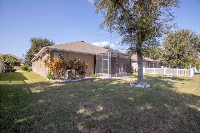 rear view of property featuring a yard and glass enclosure