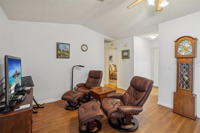 living area featuring light wood-style floors, ceiling fan, a textured ceiling, and lofted ceiling