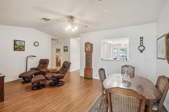 dining area featuring a ceiling fan, visible vents, vaulted ceiling, baseboards, and light wood-style floors