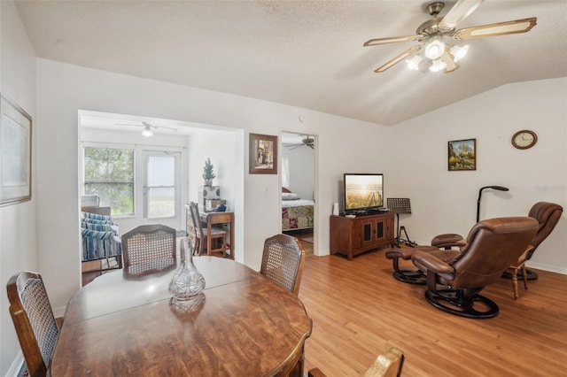 dining room featuring a textured ceiling, ceiling fan, lofted ceiling, and light wood-style floors