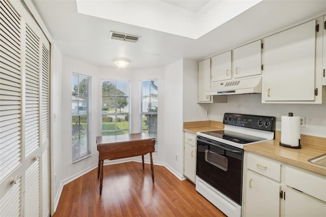 kitchen featuring visible vents, electric range, light wood-type flooring, light countertops, and under cabinet range hood