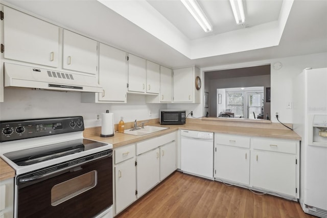 kitchen featuring white appliances, light countertops, white cabinetry, under cabinet range hood, and a sink
