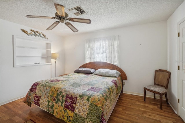 bedroom with a textured ceiling, visible vents, and wood finished floors