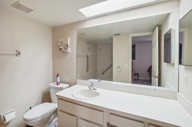 bathroom with visible vents, vanity, a shower, toilet, and a skylight