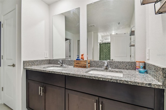 bathroom with a shower with curtain, vanity, and a textured ceiling