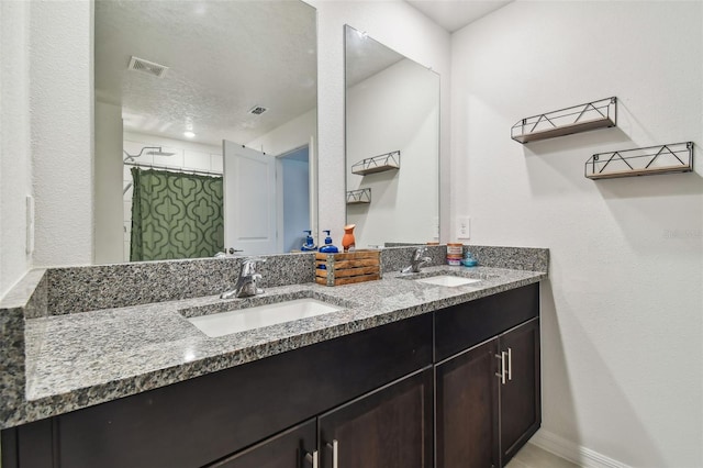 bathroom with walk in shower, vanity, and a textured ceiling