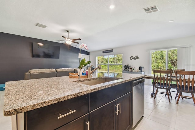 kitchen featuring light tile patterned flooring, a center island with sink, sink, stainless steel dishwasher, and lofted ceiling