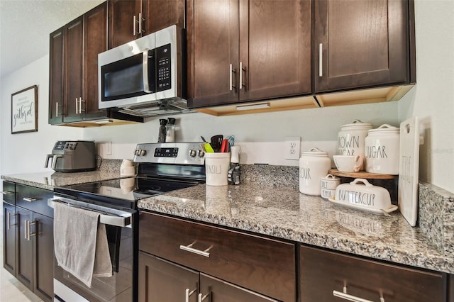 kitchen with dark brown cabinetry, appliances with stainless steel finishes, and light stone countertops