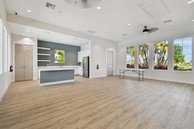 unfurnished living room with light wood-type flooring, ceiling fan, and sink