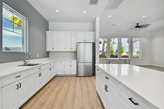 kitchen featuring white cabinetry, a wealth of natural light, sink, and stainless steel refrigerator