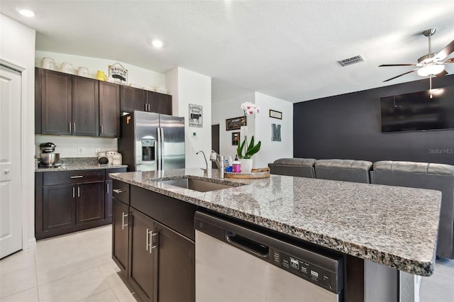 kitchen with appliances with stainless steel finishes, sink, dark brown cabinets, and a center island with sink