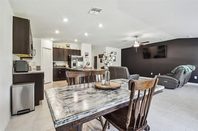 dining area with light tile patterned floors, ceiling fan, vaulted ceiling, and sink