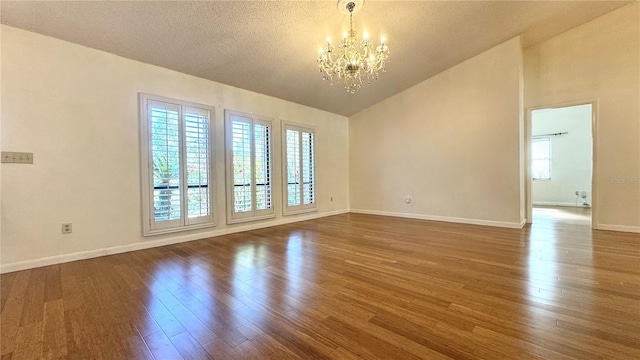 spare room featuring a textured ceiling, dark hardwood / wood-style floors, and an inviting chandelier