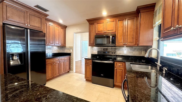 kitchen with sink, decorative backsplash, dark stone countertops, appliances with stainless steel finishes, and light tile patterned flooring