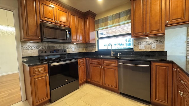 kitchen featuring dark stone countertops, sink, light tile patterned flooring, and stainless steel appliances