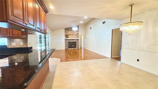 interior space with a notable chandelier, lofted ceiling, a fireplace, and light tile patterned floors