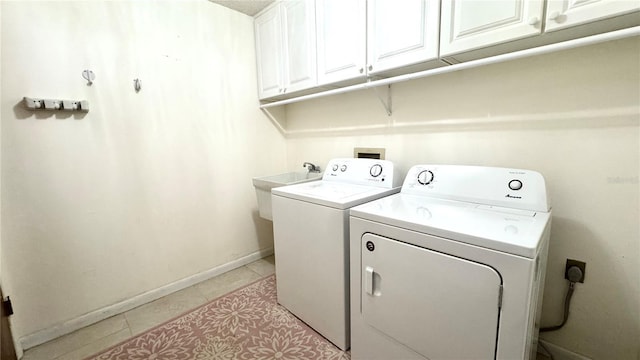 clothes washing area featuring cabinets, sink, light tile patterned floors, and washer and dryer