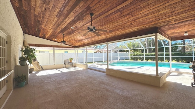 view of swimming pool featuring glass enclosure, ceiling fan, and a patio