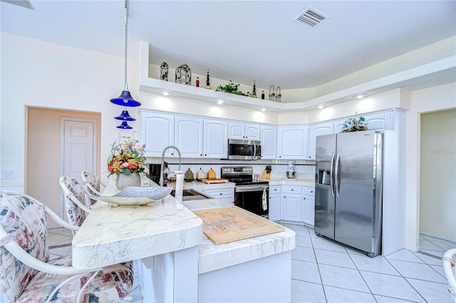 kitchen featuring kitchen peninsula, backsplash, sink, white cabinets, and appliances with stainless steel finishes