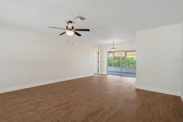 empty room featuring dark hardwood / wood-style flooring and ceiling fan with notable chandelier