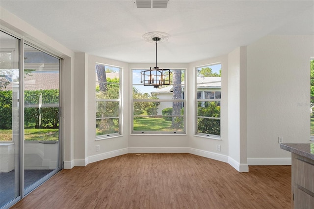 unfurnished dining area featuring hardwood / wood-style flooring and an inviting chandelier