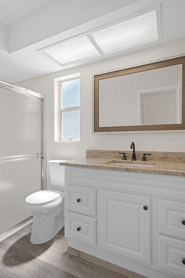 bathroom featuring vanity, walk in shower, hardwood / wood-style flooring, and toilet