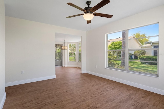 spare room featuring a healthy amount of sunlight, ceiling fan, and dark hardwood / wood-style flooring