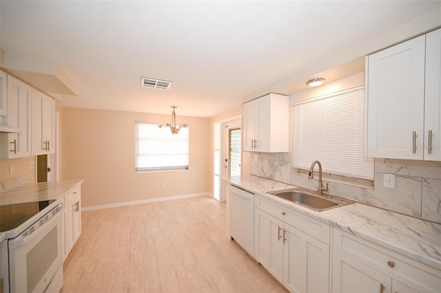 kitchen with white appliances, sink, white cabinetry, light hardwood / wood-style floors, and decorative light fixtures