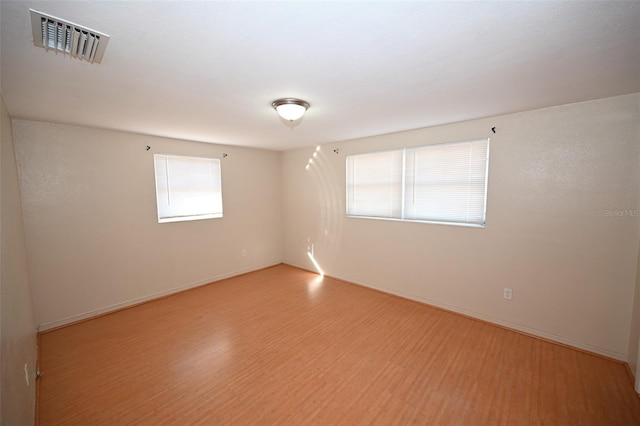 empty room with light hardwood / wood-style flooring and plenty of natural light